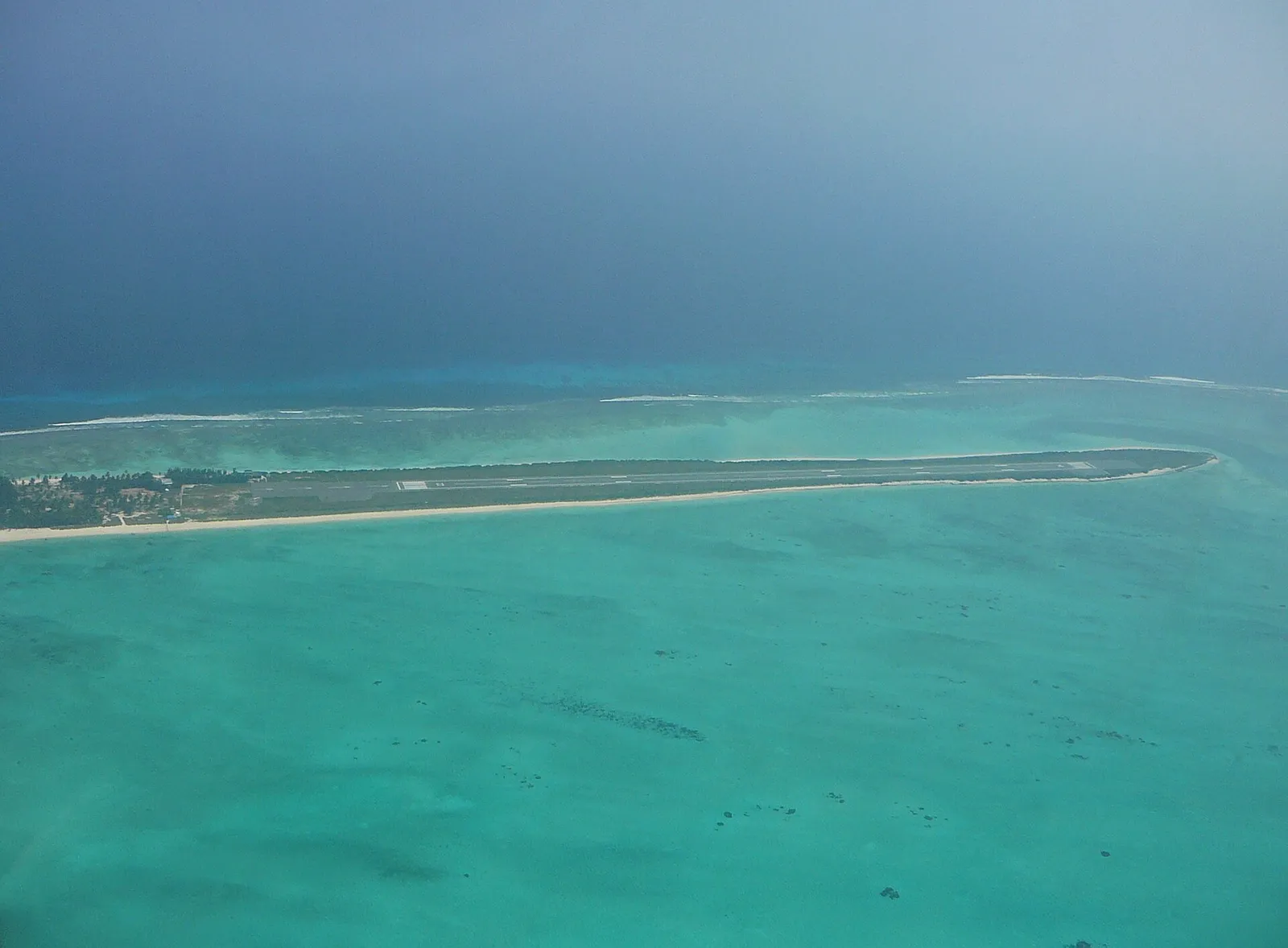 Aerial view of the airstrip on Agatti's narrow tip, surrounded by a pale turquoise lagoon and reef